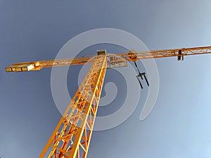 Metal construction site jib crane with pallet carrier and blue sky in the background