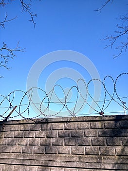 Metal cord with sharp edges on a wall made of rectangular stones under a clear blue sky