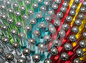 Metal cream puff chargers containing laughing gas and used as a legal high, reflecting colourful background.