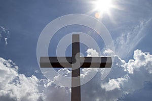 Metal cross with reflectins of the sun, blue sky with some clouds