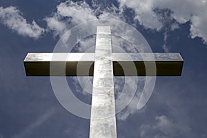 Metal cross with reflectins of the sun, blue sky with some clouds