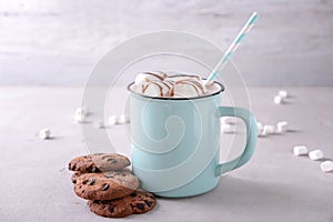 Metal cup of delicious cocoa drink with marshmallows and cookies on table
