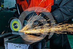 Metal cutting with an angle grinder with a cutting abrasive wheel, sparks in a workshop