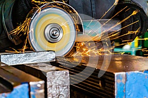 Metal cutting with an angle grinder with a cutting abrasive wheel, sparks in a workshop