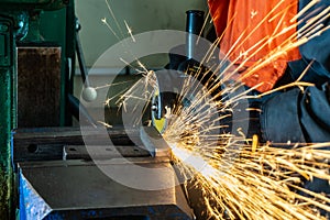 Metal cutting with an angle grinder with a cutting abrasive wheel, sparks in a workshop