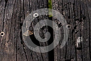Metal d20 on a scorched wooden surface in the sunlight