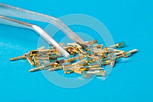 Metal dental pins on a blue background in tweezers in dentistry. Installation of pins for a dental crown in orthodontics