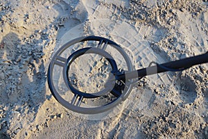 Metal detector coil looking for a treasure on sand