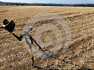 Metal detector and digging tool in stubble field