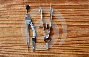 metal divider and metal drawing compass isolated on wooden background