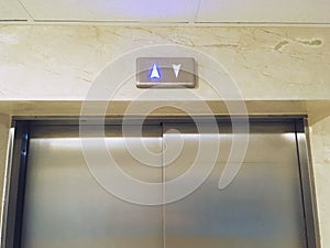 Up and down arrows of a metallic colored elevator with the up arrow illuminated. photo