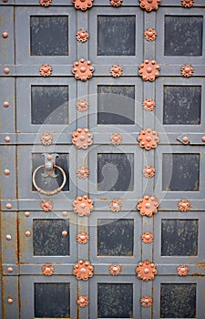 A metal door with a round handle.An old door decorated with forged elements.