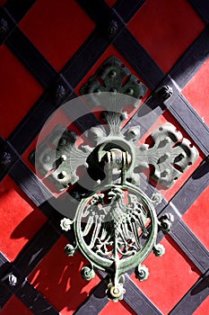 Iron-cast door knocker with eagle on the red door.