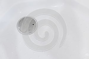 Metal drain hole in the bathtub, close-up. Drain plug close up. Drain cleaning concept, clogged and dirty sewer pipes