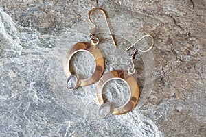 Metal earrings in ornamental shape hanging on neutral background