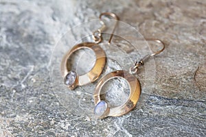 metal earrings in ornamental shape hanging on neutral background