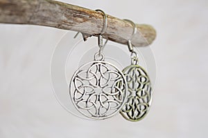 metal earrings in ornamental shape hanging on neutral background