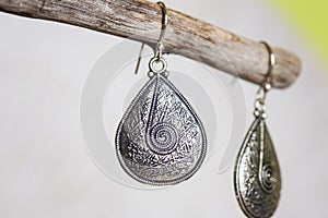 metal earrings in ornamental shape hanging on neutral background