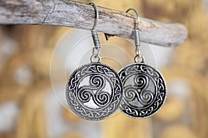 metal earrings in ornamental shape hanging on neutral background