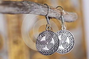 metal earrings in ornamental shape hanging on neutral background