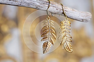 Metal earrings in ornamental shape hanging on neutral background