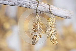 metal earrings in ornamental shape hanging on neutral background