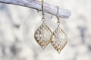 metal earrings in ornamental shape hanging on neutral background