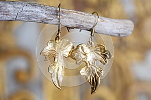 Metal earrings in ornamental shape hanging on neutral background