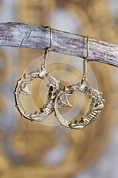 metal earrings in ornamental shape hanging on neutral background