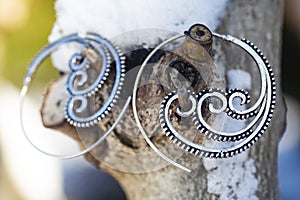 Metal earrings on outdoor natural background