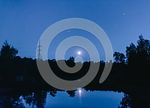Metal electric poles in the moonlight at the lake