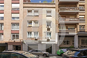 Metal entrance portal on th e of a three-story residential building on a street with parked vehicles photo