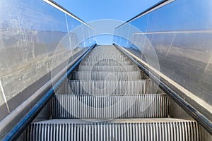 Metal escalator outdoors with blue sky