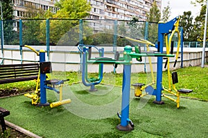 Metal exercise machines in bright colors on a sports field with a rubberized coating against a background