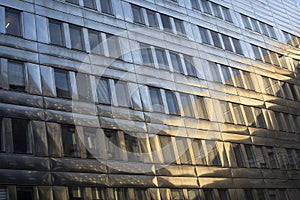 Metal  facade on modern business building with reflection from another building