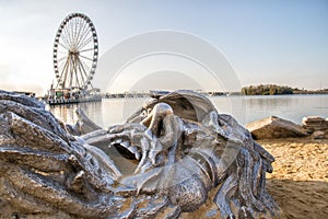 Metal face sculpture in the sand by the ocean