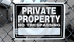 Metal Fence with Black and White Private Property No Trespassing Warning Sign Close Up