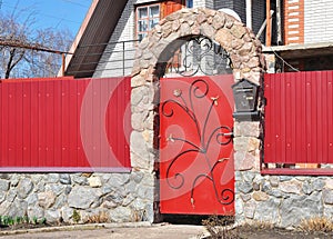 Metal Fence Door with red wild stone. Metal fencing exterior with door bell and postbox.