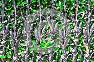 Metal fence in shape of cornstalks holding back green hedge. photo