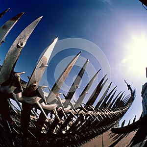 Metal fence with sharp spikes against blue sky