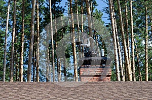 Metal figure of a stork on the roof of a country house