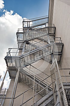 Metal fire escape stairs construction outdoor side of high building and blue sky with clouds. Pompier ladder. photo