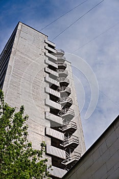 Metal fire escape stairs construction outdoor side of high building and blue sky with clouds. Pompier ladder. photo