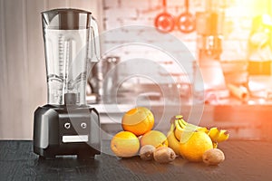 Metal food blender close-up with fresh exotic tropic fruits next to it on kitchen background with empty space. Sun flare