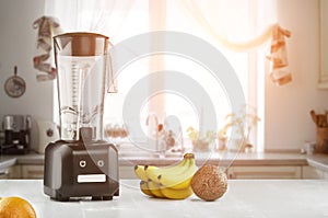 Metal food blender close-up with fresh exotic tropic fruits next to it on kitchen background with empty space. Sun flare