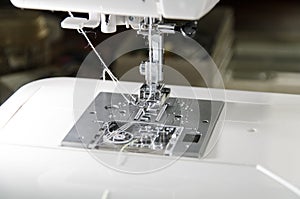 Metal foot with a needle and thread in a modern sewing machine