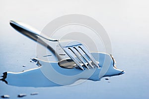Metal fork on a large water drop on a clean surface
