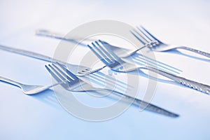 . Metal forks with shadows isolated on a white table.