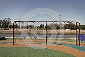 Metal four seat swings outdoors. Childrens swings on playground. Swings seats suspended by chains