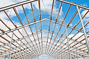 Metal frame of the new building against the blue sky with clouds.